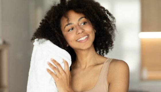 Smiling african american woman drying wet hair with towel after shower